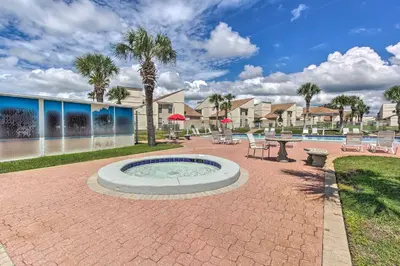 a patio with a hot tub and tables and chairs at Cozy PCB Condo Less Than half Mile to Public Beach Access! in Panama City Beach