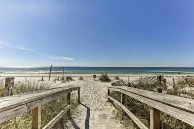 a wooden bench on a sandy beach near the ocean at Panama City Beach Townhome - Walk to Beach! in Panama City Beach