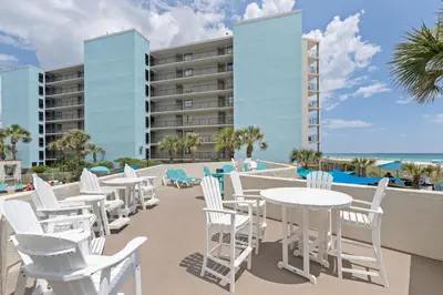 a row of white chairs and tables on the balcony of a resort at Top of The Gulf 213 in Panama City Beach
