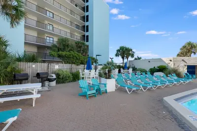 a patio with blue chairs and a swimming pool at Top of The Gulf 213 in Panama City Beach