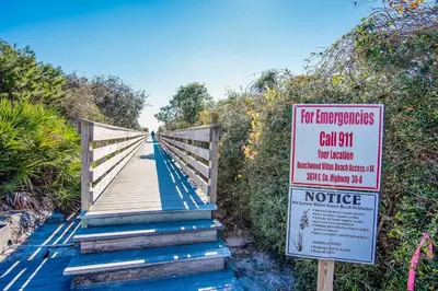 a sign on a wooden bridge with afor emergencies call at Beachwood Villas 12C in Santa Rosa Beach