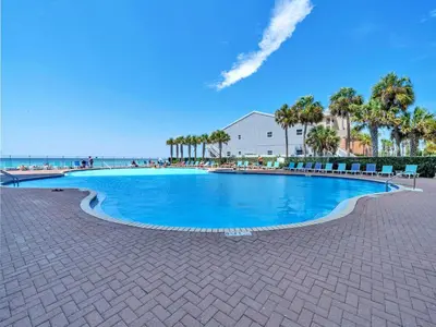 a large swimming pool next to a beach with palm trees at Tidewater 1810 in Panama City Beach