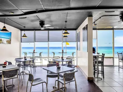a restaurant with tables and chairs and a view of the ocean at Tidewater 1810 in Panama City Beach