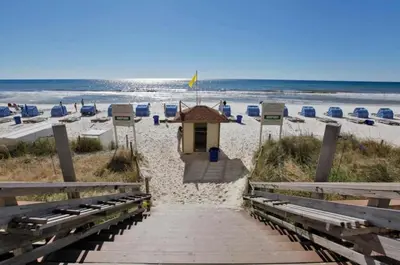 a building on a beach with chairs and the ocean at Tidewater 1909 in Panama City Beach