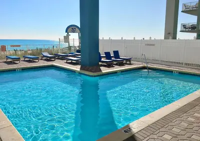 a large swimming pool with chairs and the ocean at Grandview East 404 in Panama City Beach