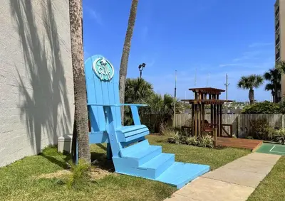 a blue chair sitting next to a palm tree at Top of the Gulf 822 in Panama City Beach