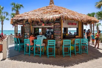 a bar with chairs and a straw umbrella on the beach at Calypso Beach Resort & Towers by Panhandle Getaways in Panama City Beach