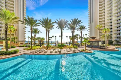 a swimming pool with palm trees and buildings at Shores of Panama 1523 in Panama City Beach