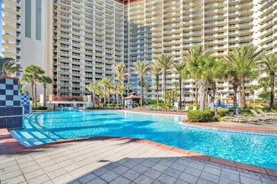 a swimming pool with palm trees and a large building at Shores of Panama 1523 in Panama City Beach