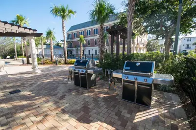 two bbqs and a grill in a courtyard with palm trees at Village Of South Walton #263A in Rosemary Beach