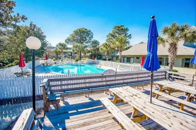 a pool with two benches and umbrellas at Beachwood Villas 1A- Beach Haven in Santa Rosa Beach