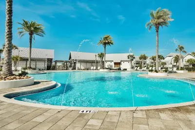 a swimming pool with palm trees in a resort at Prominence 30A - Coastal Cottage in Panama City Beach