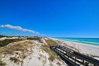 a bench on a sandy beach next to the ocean at Paradise Found on 30A in Santa Rosa Beach