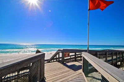 a boardwalk leading to the beach with a red flag at Seas The Day 30A in Santa Rosa Beach