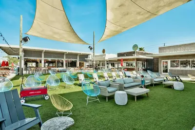 an outdoor seating area with chairs and tables and an umbrella at Prominence 30A - Hey Hey 30A in Inlet Beach