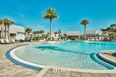 a swimming pool with palm trees in a resort at Settle By The Sea in Inlet Beach