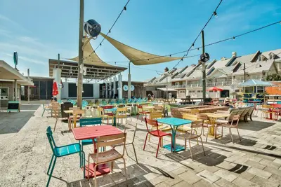 a group of tables and chairs with tables and chairs at Settle By The Sea in Inlet Beach