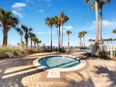 a swimming pool with palm trees and a fence at Grand Panama Beach Resort - The Grand #403 in Panama City Beach