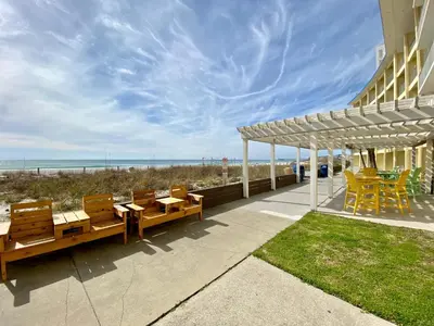 a patio with tables and chairs next to the beach at Continental Condominiums 3 in Panama City Beach