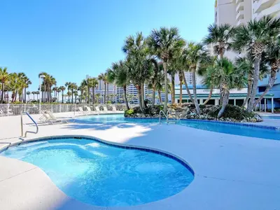 a swimming pool with palm trees and a building at Long Beach Resort Tower II #904 in Panama City Beach