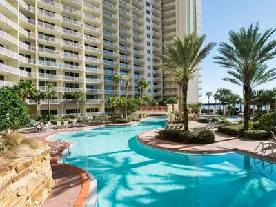 a resort swimming pool with palm trees and a large building at Shores of Panama #1425 in Panama City Beach