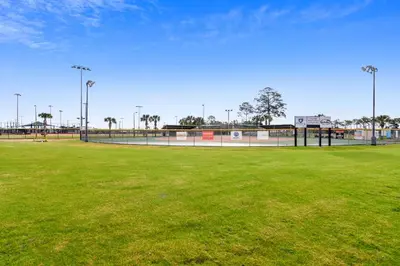 a baseball field with green grass and lights on it at Splash Pad by Book That Condo in Panama City Beach