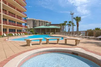 a swimming pool with benches in front of a hotel at Hidden Dunes 901 in Panama City Beach