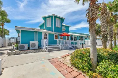 a blue house with palm trees in front of it at Gulf Highlands 220 in Panama City Beach