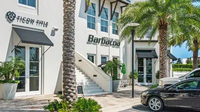 a hotel with palm trees in front of a building at Lazy Days in Seacrest