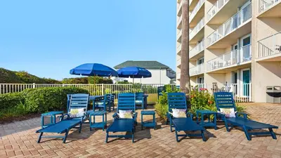 a group of blue chairs and umbrellas next to a building at Beachcrest 1204 in Santa Rosa Beach