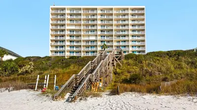 a building on the beach with a wooden staircase leading to the beach at Beachcrest 1204 in Santa Rosa Beach