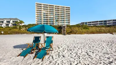 two beach chairs and an umbrella on the beach at Beachcrest 402 in Santa Rosa Beach