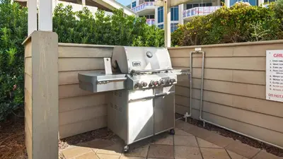a barbecue grill sitting next to a fence at Beachcrest 601 in Santa Rosa Beach