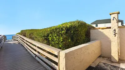 a wooden boardwalk next to a building and the ocean at Beachcrest 603 in Santa Rosa Beach