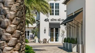 a facade of a white building with a stone wall at Inn At Seacrest 405 in Rosemary Beach