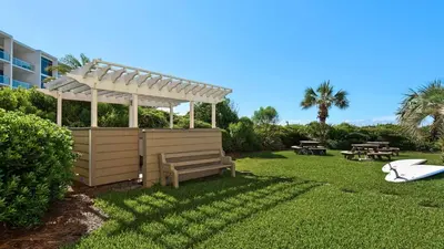 a pergola and a bench in a yard at Beachcrest 906 in Santa Rosa Beach
