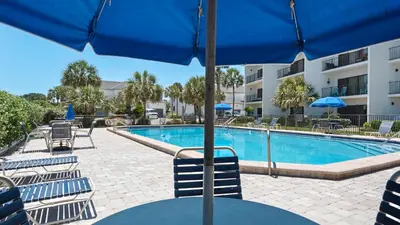 a pool with chairs and a table with an umbrella at Emerald Hill 12A in Santa Rosa Beach