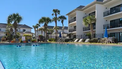 a swimming pool in front of a building with palm trees at Emerald Hill 12A in Santa Rosa Beach