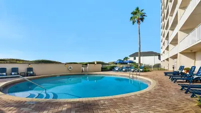 a swimming pool with chairs and a palm tree at Beachcrest 1201 in Santa Rosa Beach
