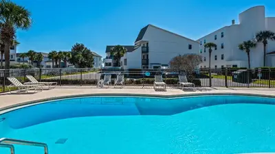 a swimming pool with chairs and a building at Beachside Condo 11 in Santa Rosa Beach