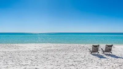two chairs sitting on a beach next to the ocean at Beachside Condo 14 in Santa Rosa Beach