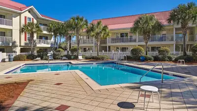 a swimming pool in front of a building with palm trees at Rollin Tide C2 - Seaglass Sands in Santa Rosa Beach