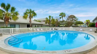 a large swimming pool with palm trees and a fence at Beachwood Villas 3H in Santa Rosa Beach