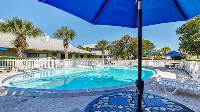 a swimming pool with an umbrella and chairs and tables at Beachwood Villas 7F in Santa Rosa Beach