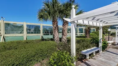 a white pergola and a bench in front of a building at Beachwood Villas 9B in Santa Rosa Beach