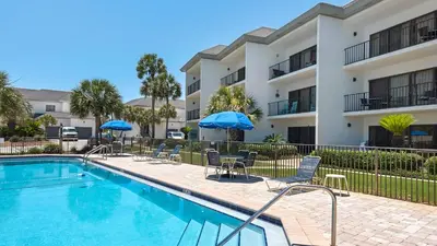 a swimming pool with chairs and umbrellas in front of a building at Emerald Hill 1 in Santa Rosa Beach
