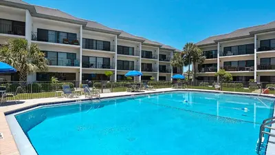 a pool with chairs and umbrellas in front of a hotel at Emerald Hill 11 in Santa Rosa Beach