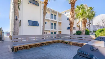 a park bench in front of a building with palm trees at Eastern Shores 201 - A Happy Little Condo in Santa Rosa Beach