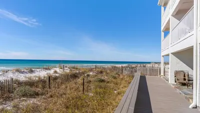 a beach house with a boardwalk leading to the beach at Eastern Shores 201 - A Happy Little Condo in Santa Rosa Beach