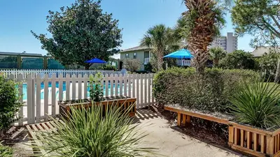 a white fence with benches and plants in a yard at Beachwood Villas 11E - SE Seagrove in Santa Rosa Beach